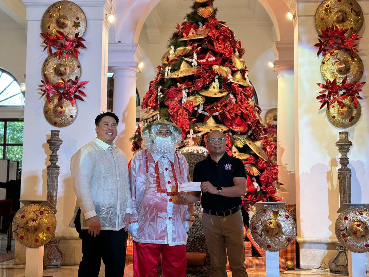 Filipino Santa Claus hands the check to Ricky Bhunao of the House of Refuge Foundation as Marvin Kim Tan looks on.