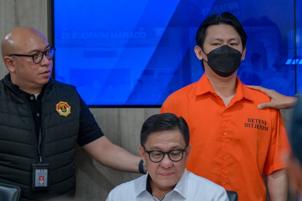 Indonesian immigration officers escort Filipino fugitive Hector Aldwin Liao Pantollana (R) during a press conference in Jakarta on November 26, 2024.