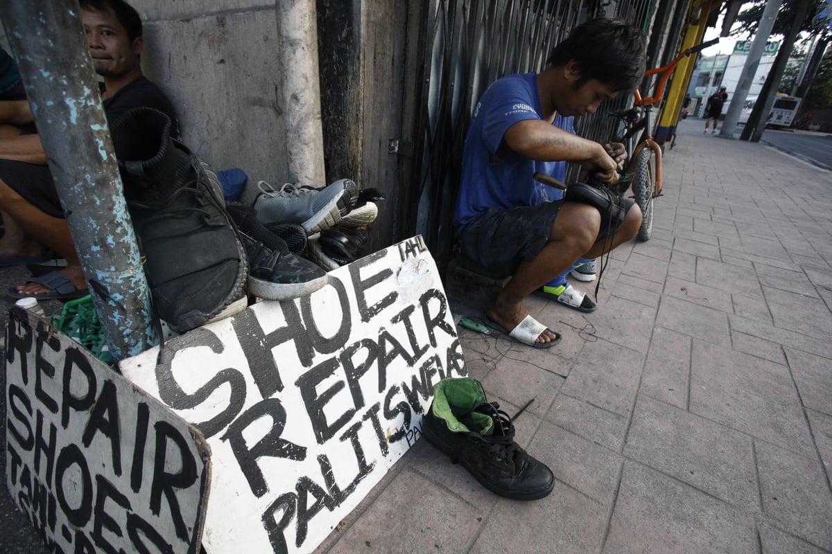 Jaymar sits and works beside his sign that reads "Palit Swelas" (change soles) as he carefully mends a pair of shoes. This makeshift shop has become a testament to Marikina City's enduring legacy of shoemaking and craftsmanship.