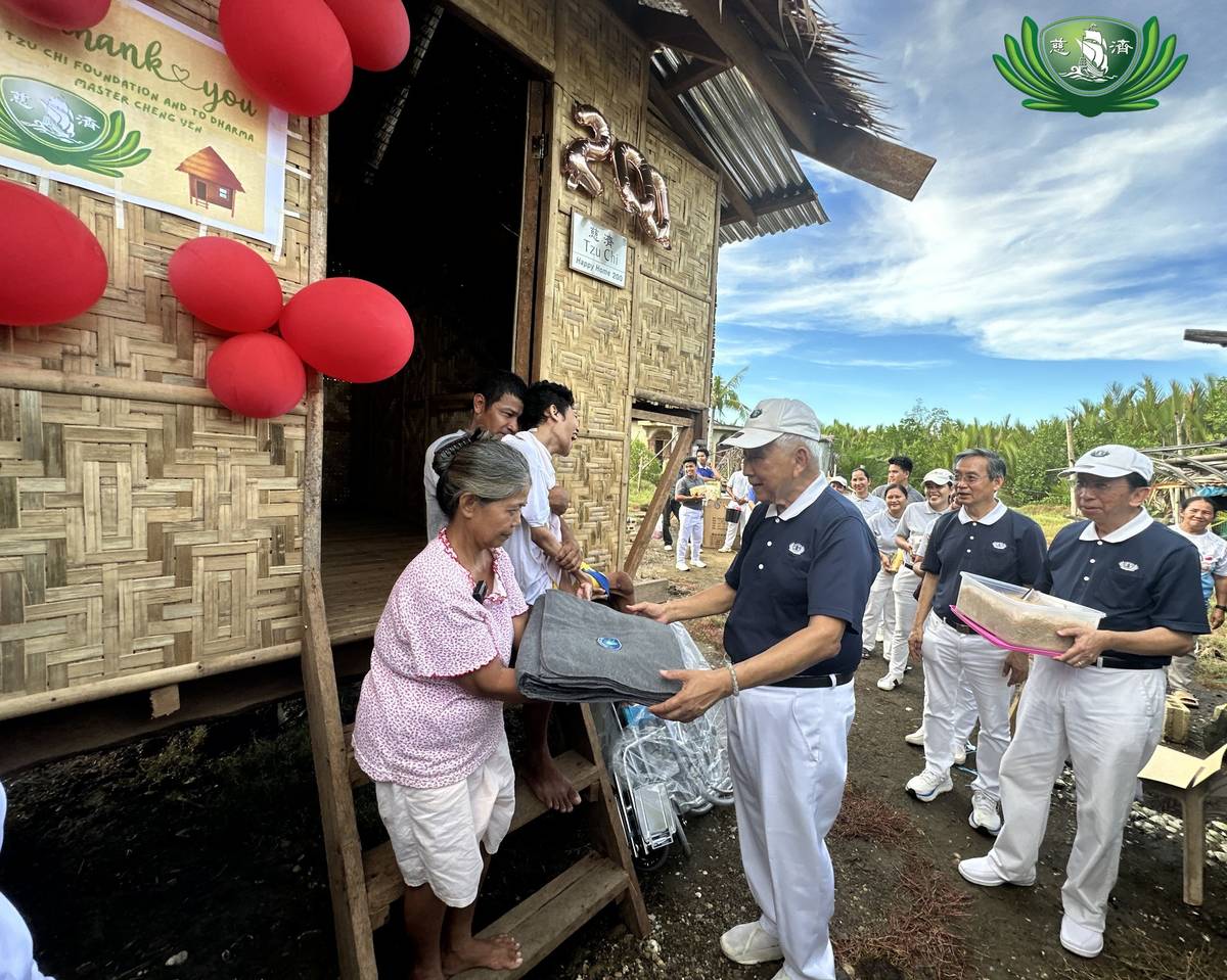 Evangelina Luzon (left) receives donated blankets from a Tzu Chi Bohol volunteer during the turnover of their new home built by volunteers from Tzu Chi Bohol in Inabanga town. The 200th Happy Home, which replaced Luzon’s house that was destroyed by typhoon ‘Odette’ now provides comfort living to her husband, Renato, and their son, Dodong, who also received a wheelchair from the charity organization.
