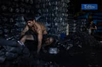 (From L-R) Marvin Nares, 32, and Nadir Arob, 34, pack charcoal inside a warehouse at Commonwealth Market, Quezon City, Friday, 6 December.
Arob, originally from Marawi City, said he has worked at the charcoal store for 14 years. Meanwhile, Nares, who hails from Bicol, said he has been working there for a year but has experience in similar jobs with other companies.
Both workers said they earn P500 per day and work seven days a week unless they request a day off or vacation.