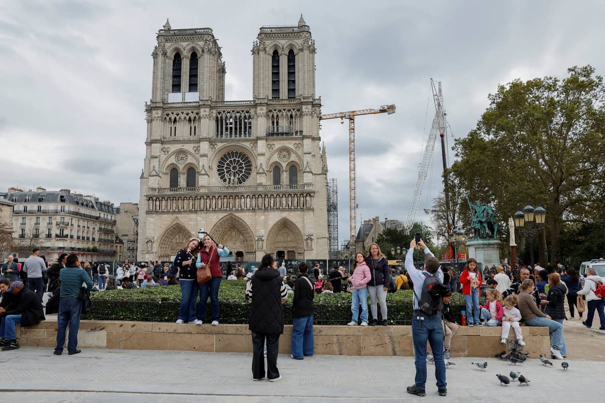 Visitors take photographs with Notre-Dame de Paris Cathedral in Paris on 25 October 2024, which is due to reopen to the public on 8 December 2024. French ministers have raised the idea of charging tourists to enter Paris' world-famous Notre-Dame cathedral when it opens in December 2024 after a five-year restoration due to its partial destruction when a fire broke out in 2019, a proposal that drew a rebuke from the city's diocese on 24 October 2024.