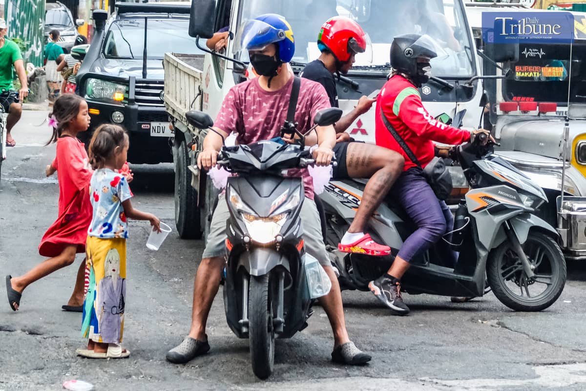 Children approach a motorcycle rider to ask for 'pamasko' along Osmeña Highway, just 12 days before Christmas.