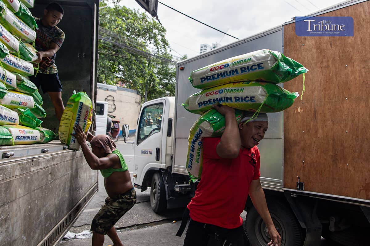 Workers load and unload sacks of rice along Dagupan Street in Divisoria, Manila, on Wednesday, 18 December 2024.