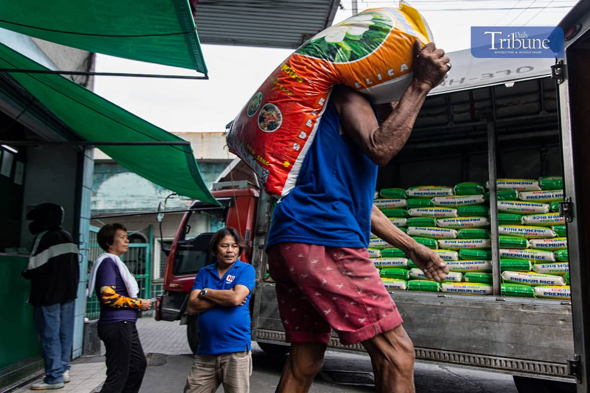 Workers load and unload sacks of rice along Dagupan Street in Divisoria, Manila, on Wednesday, 18 December 2024.