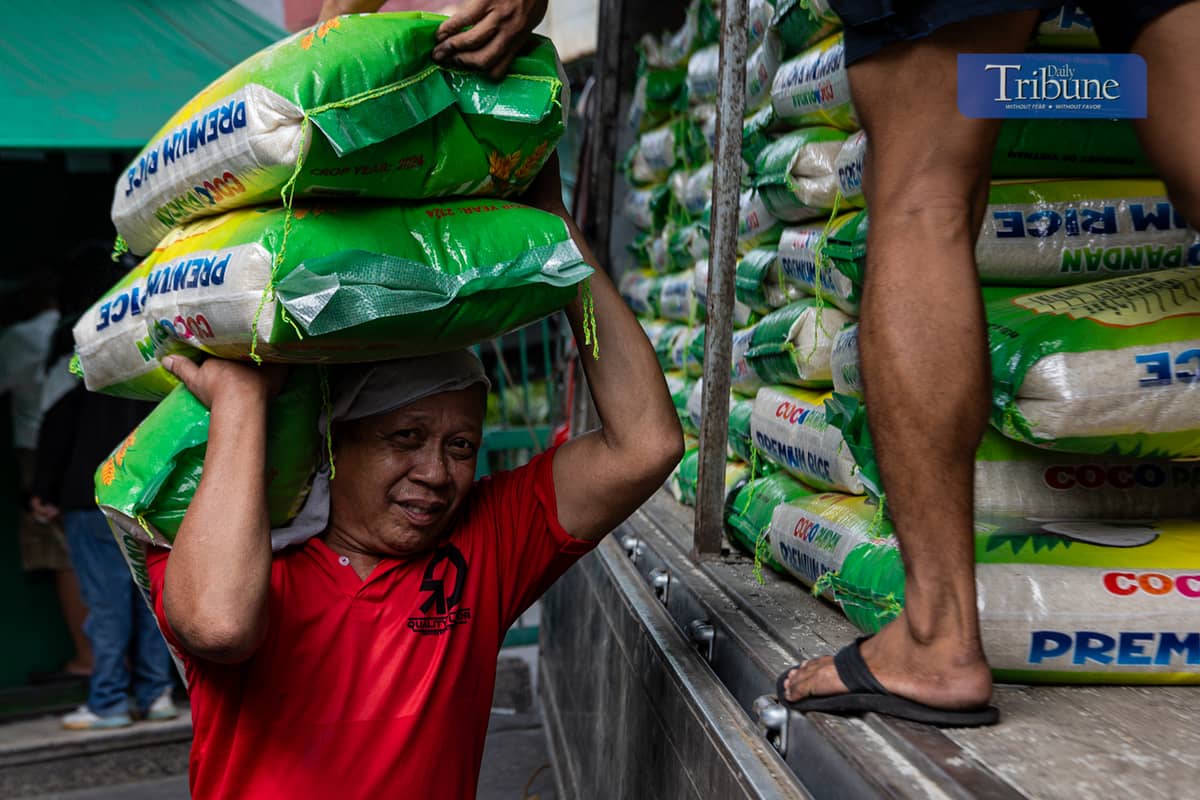 Workers load and unload sacks of rice along Dagupan Street in Divisoria, Manila, on Wednesday, 18 December 2024.