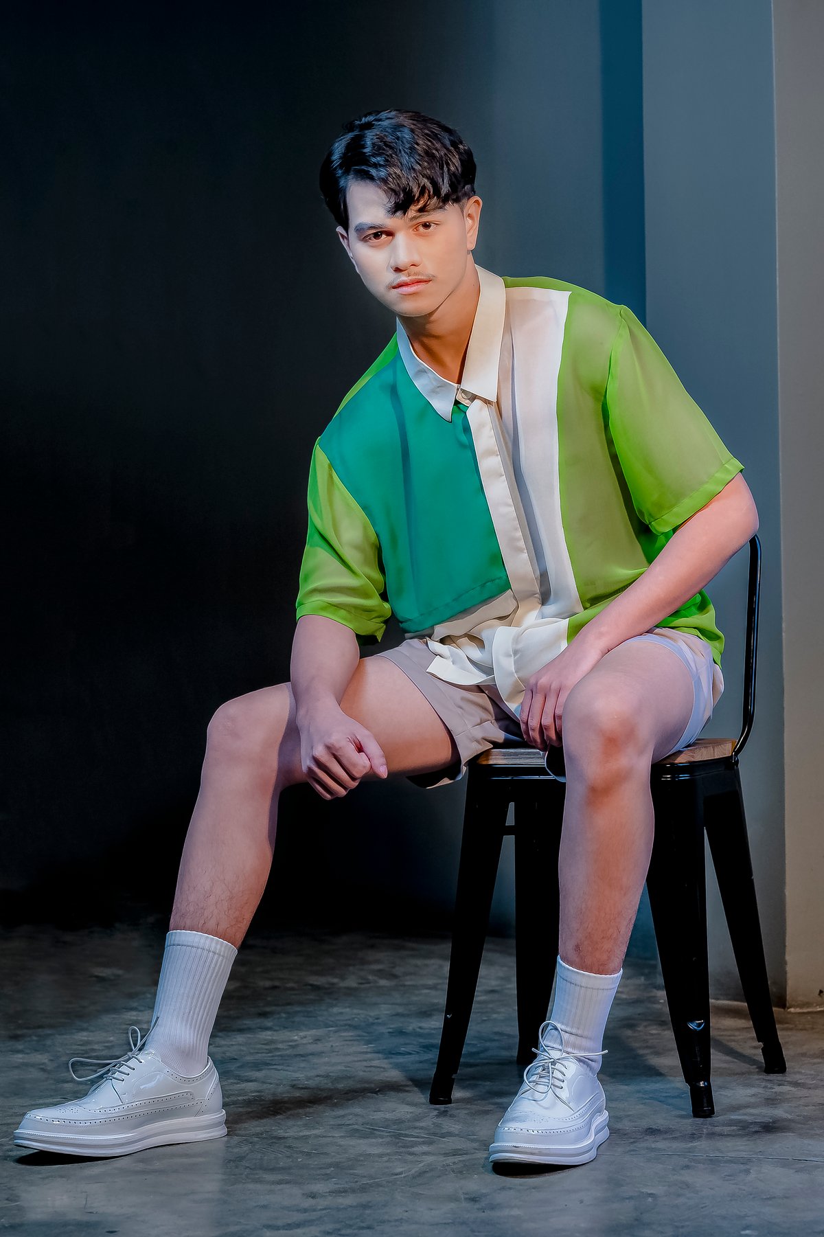 On Dave Flores are layers of soft Cerutti chiffon in emerald, lime and off-white forming a short-sleeved shirt, paired with soft beige tailored shorts, both inspired by Romulo Olazo’s Diaphanous B-CLXXXIII (2012, oil on canvas). It is styled with white socks and white shoes.