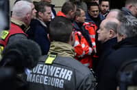 German Chancellor Olaf Scholz (R) talks to rescuers during a visit to the site of a car-ramming attack on a Christmas market in Magdeburg, eastern Germany, on 21 December, 2024, resulting in several deaths and dozens of injured. German media reports that the death toll has risen to four over night and up to 200 injured in the attack on 20 December.