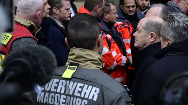 German Chancellor Olaf Scholz (R) talks to rescuers during a visit to the site of a car-ramming attack on a Christmas market in Magdeburg, eastern Germany, on 21 December, 2024, resulting in several deaths and dozens of injured. German media reports that the death toll has risen to four over night and up to 200 injured in the attack on 20 December.
