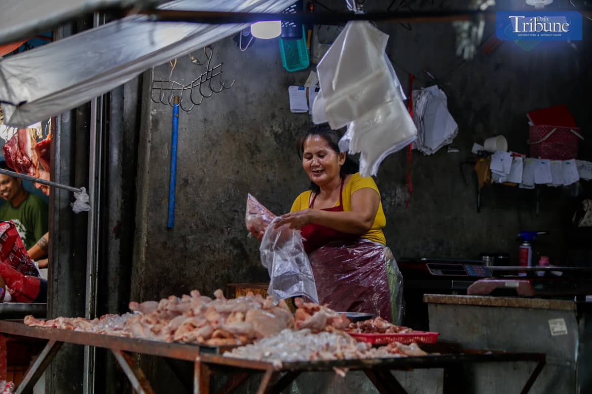 A woman packs dressed chicken at her shop in Mega Q-Mart, Quezon City, on Sunday, 22 December 2024, as vendors report a P20 increase in chicken prices, with unbranded chicken now costing P200 per kilo.