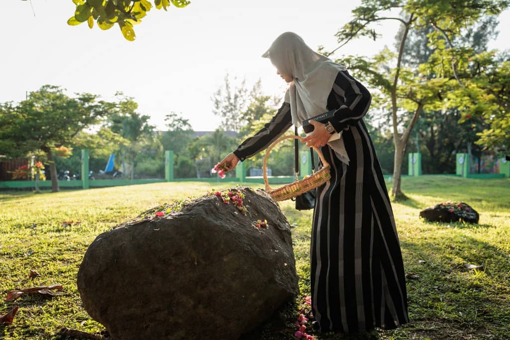 A mourner scatters flower petals at the Ulee Lheue mass grave, one of the two major mass burial sites where victims of the 2004 Indian Ocean tsunami were laid to rest, in Banda Aceh on 26 December 2024, the 20th anniversary of the tsunami. Tearful mourners prayed on 26 December as ceremonies began across Asia to remember the 220,000 people who died two decades ago when a tsunami hit coastlines around the Indian Ocean, in one of the world's worst natural disasters.