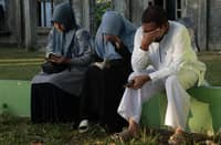 Mourners react as they gather at a mass grave in Indonesia's Aceh Province 20 years after the tsunami