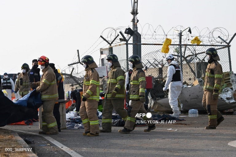 Firefighters and rescue personnel work near the scene where a Jeju Air Boeing 737-800 series aircraft crashed and burst into flames at Muan International Airport in South Jeolla Province, some 288 kilometres southwest of Seoul on December 29, 2024. A Jeju Air plane carrying 181 people from Bangkok to South Korea crashed on arrival December 29, colliding with a barrier and bursting into flames, with only two survivors rescued so far and 120 confirmed dead.