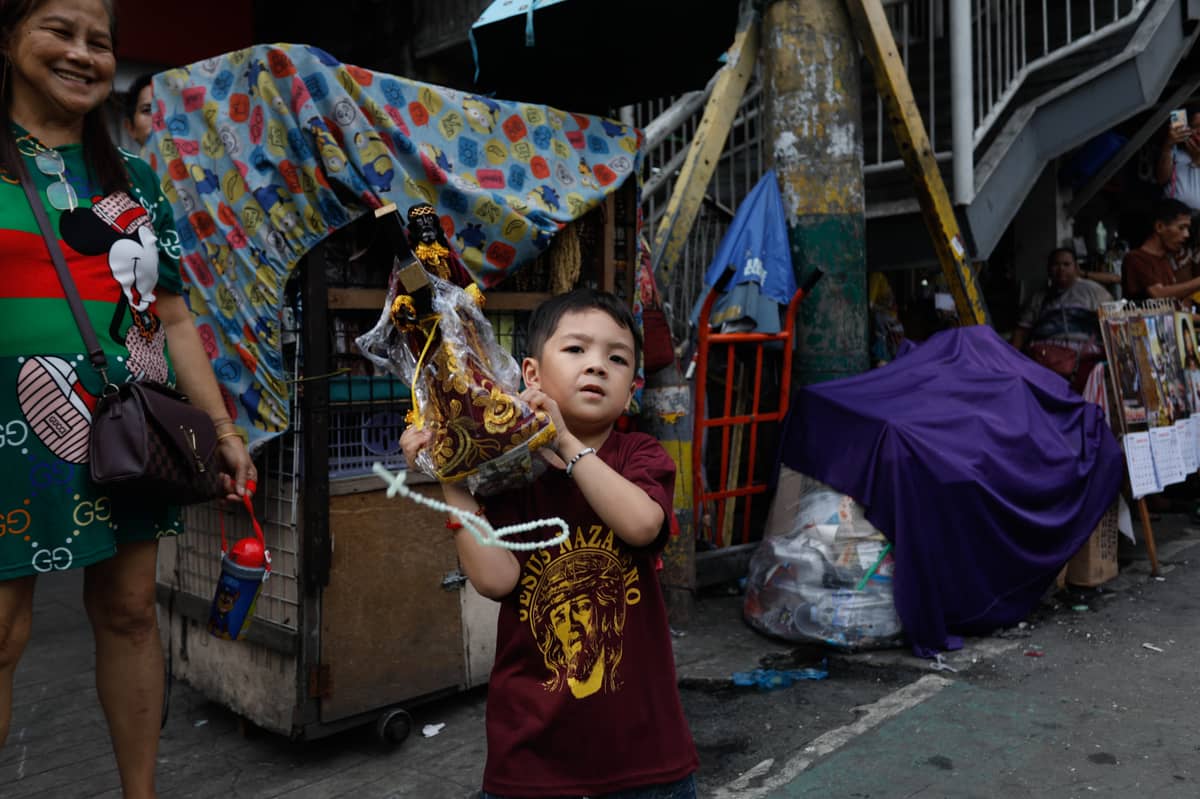 A boy drops the rosary placed on the miniature Black Nazarene figure while shaking it in an attempt to show support for the idol.