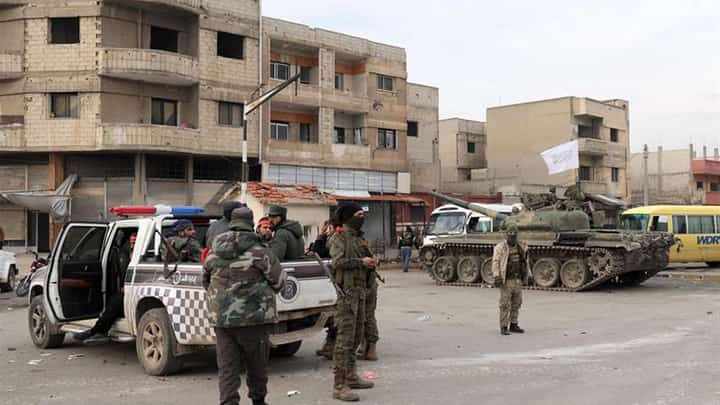 Fighters and security forces loyal to the interim Syrian government stand at a checkpoint in the Zahra district of Syria's west-central city of Homs.