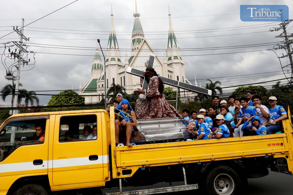 Devotees of the Jesus Nazarene ride an elf carrying a life-size Nazarene image past an Iglesia Ni Cristo Church on Commonwealth Avenue, Quezon City, on Wednesday, 8 January 2024.