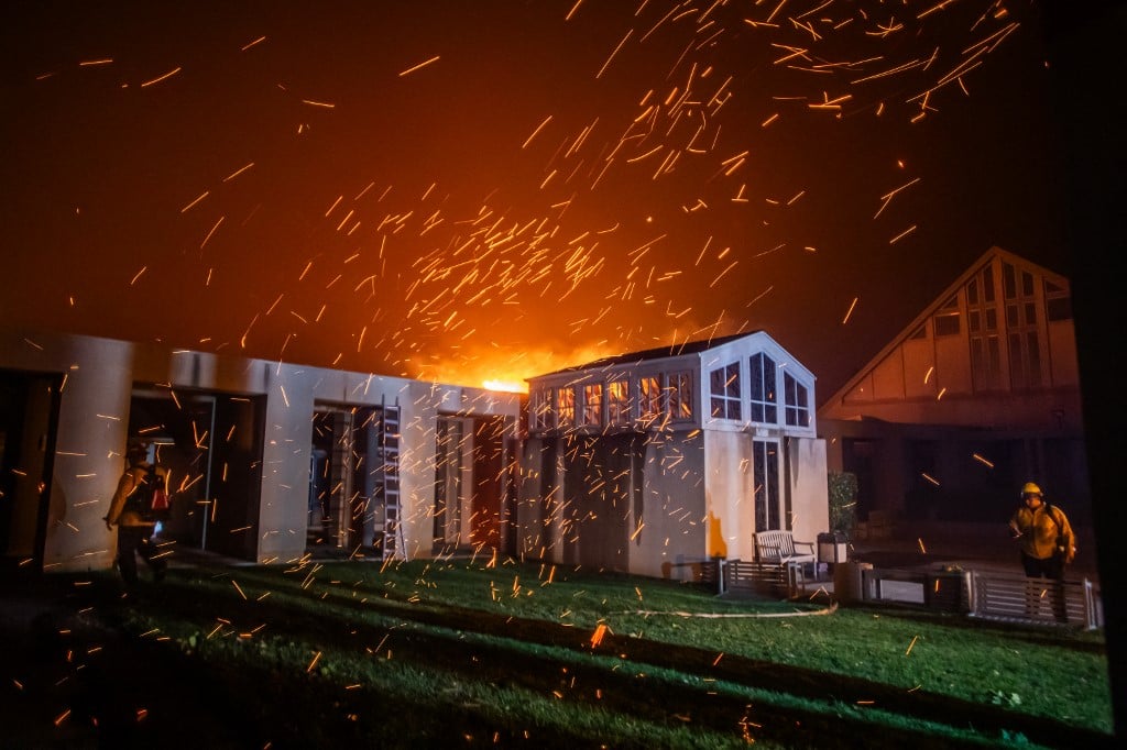A Firefighter watches the flames from the Palisades Fire burning in front of the Pacific Palisades Presbyterian Church during a powerful windstorm on January 8, 2025 in the Pacific Palisades neighborhood of Los Angeles, California. The fast-moving wildfire is threatening homes in the coastal neighborhood amid intense Santa Ana Winds and dry conditions in Southern California.