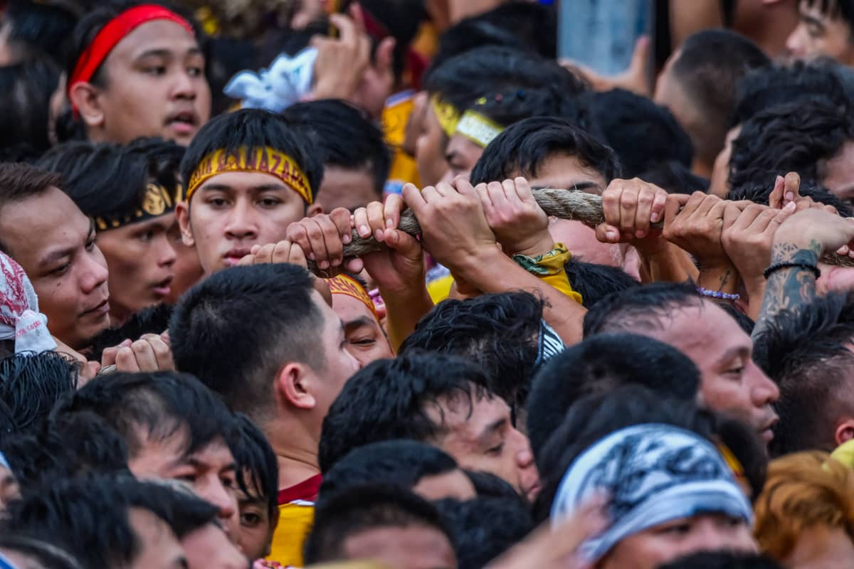 Devotees strive to reach the ropes to help pull the andas.