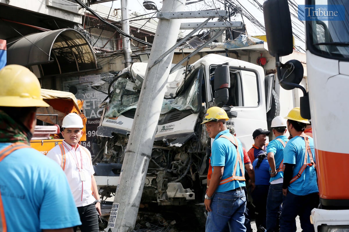 Meralco and MMDA personnel coordinate to move a truck that collided with a post.