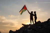 A boy runs with a Palestinian flag atop a mound of rubble at a camp for people displaced by conflict in Bureij in the central Gaza Strip on January 17, 2025 following the announcement of a truce amid the ongoing war between Israel and Hamas.