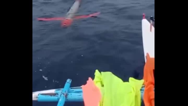 Screenshot of the silver and red drone caught on video drifting near a fishing vessel.