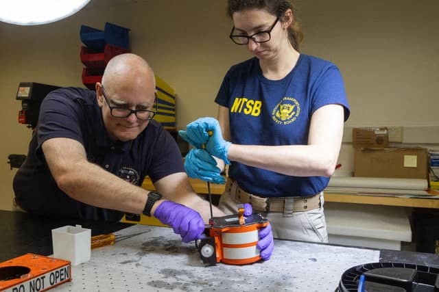 This image obtained on 31 January 2025, from the National Transportation Safety Board (NTSB) in Washington, DC, shows NTSB investigators inspecting a black box from American Airlines flight 5342. Investigators recovered the black boxes from the plane that collided mid-air with a military helicopter over Washington's Potomac River late on 29 January killing all 67 people, as rescuers pulled bodies from the freezing water.