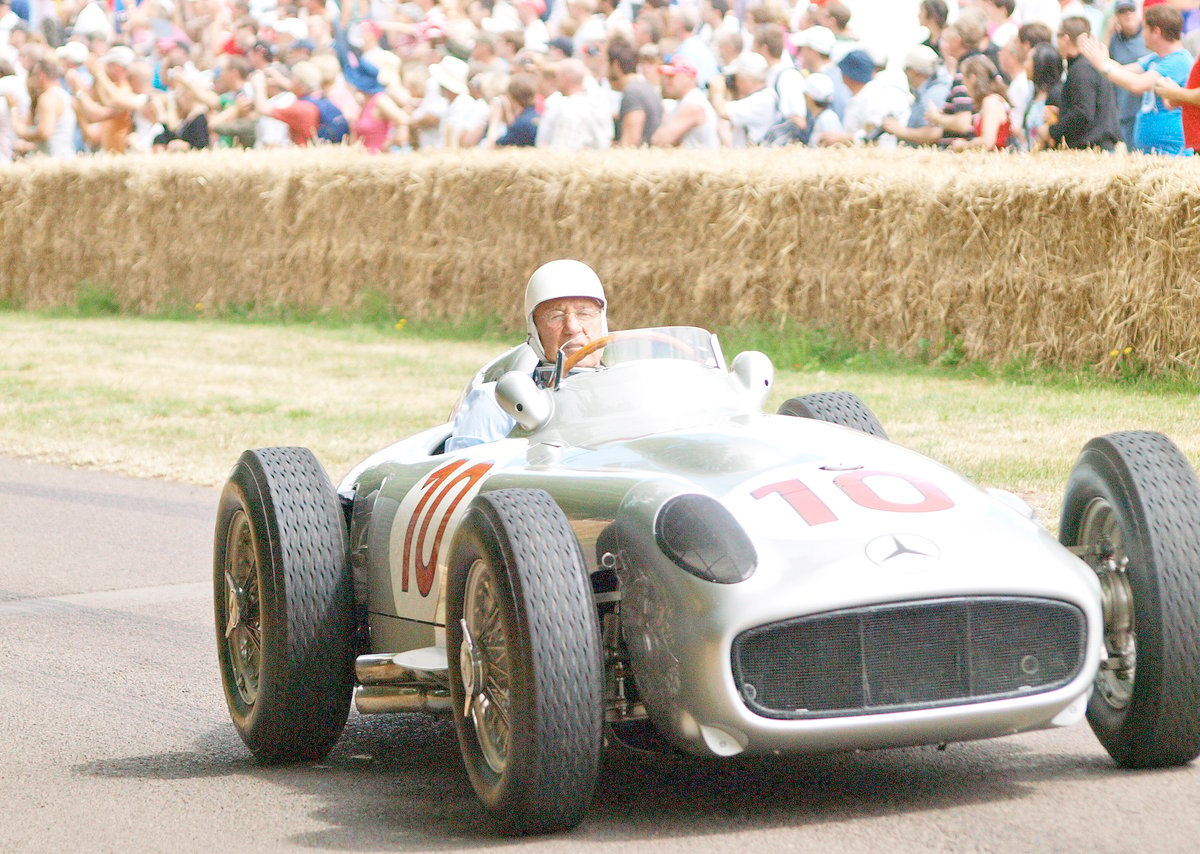 STIRLING Moss in his 1954 Mercedes Benz W196 racing car drives past the crowds.