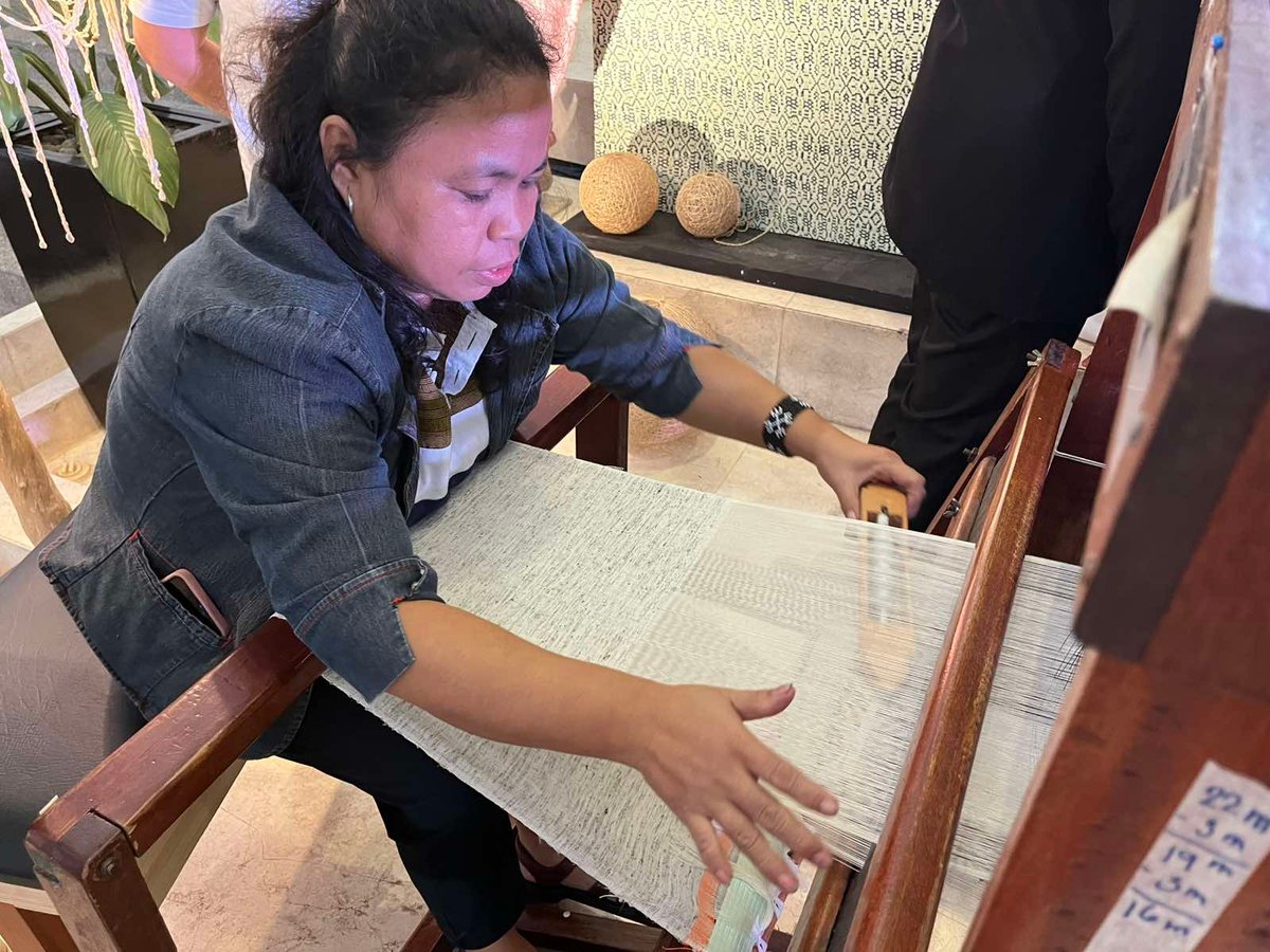 A woman demonstrates the craft of weaving in action.