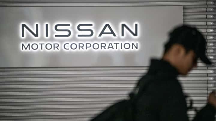 This file photo taken on 10 February 2025 shows a man walking past the Nissan logo in the showroom at Nissan's global headquarters in Yokohama, Kanagawa prefecture.