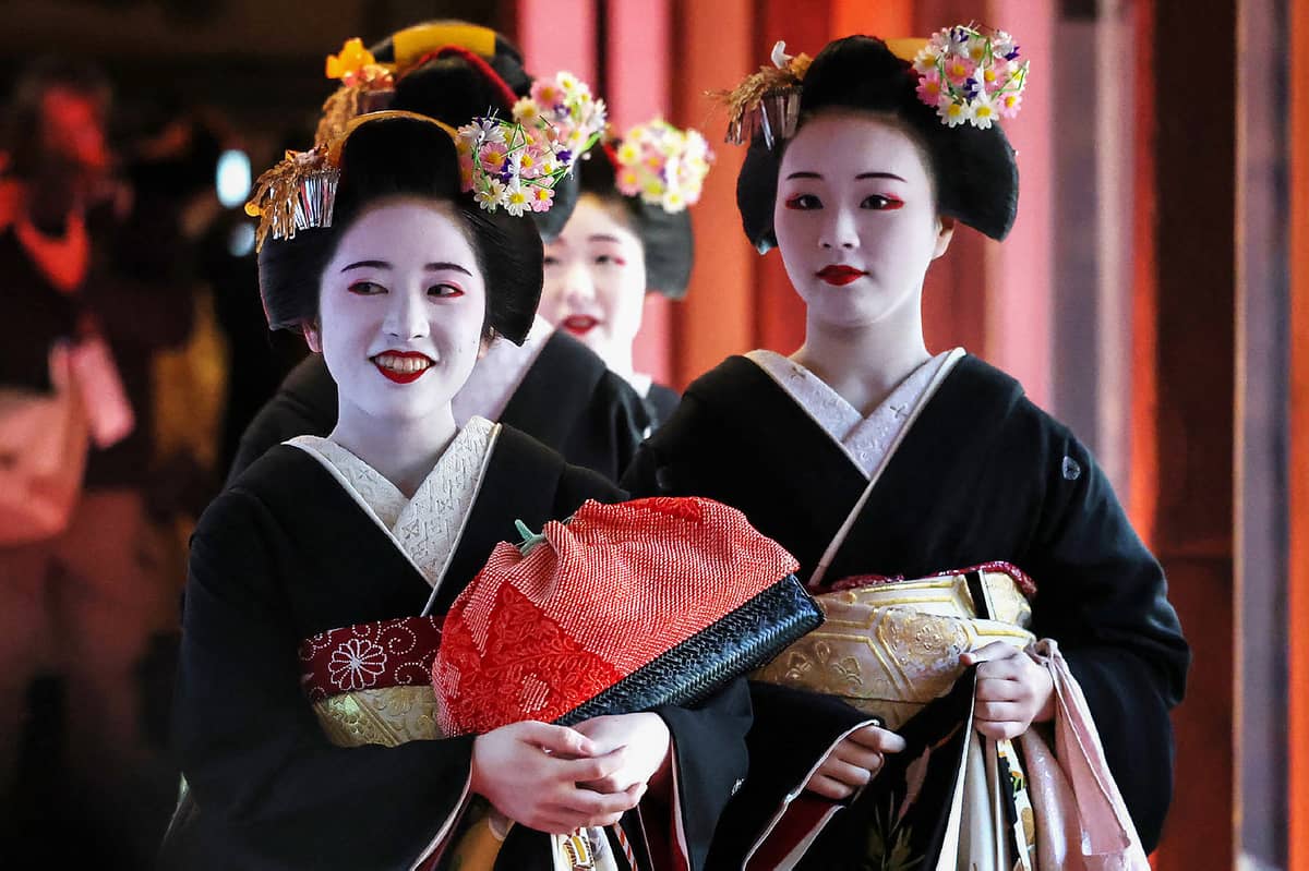 Geisha and maiko (apprentice geisha), dressed in traditional formal costumes with black crests and hairpins made of rice, attend an opening ceremony with other related parties at a venue to exchange New Year's greetings, in the entertainment district of Gion in Kyoto on 7 January 2025.