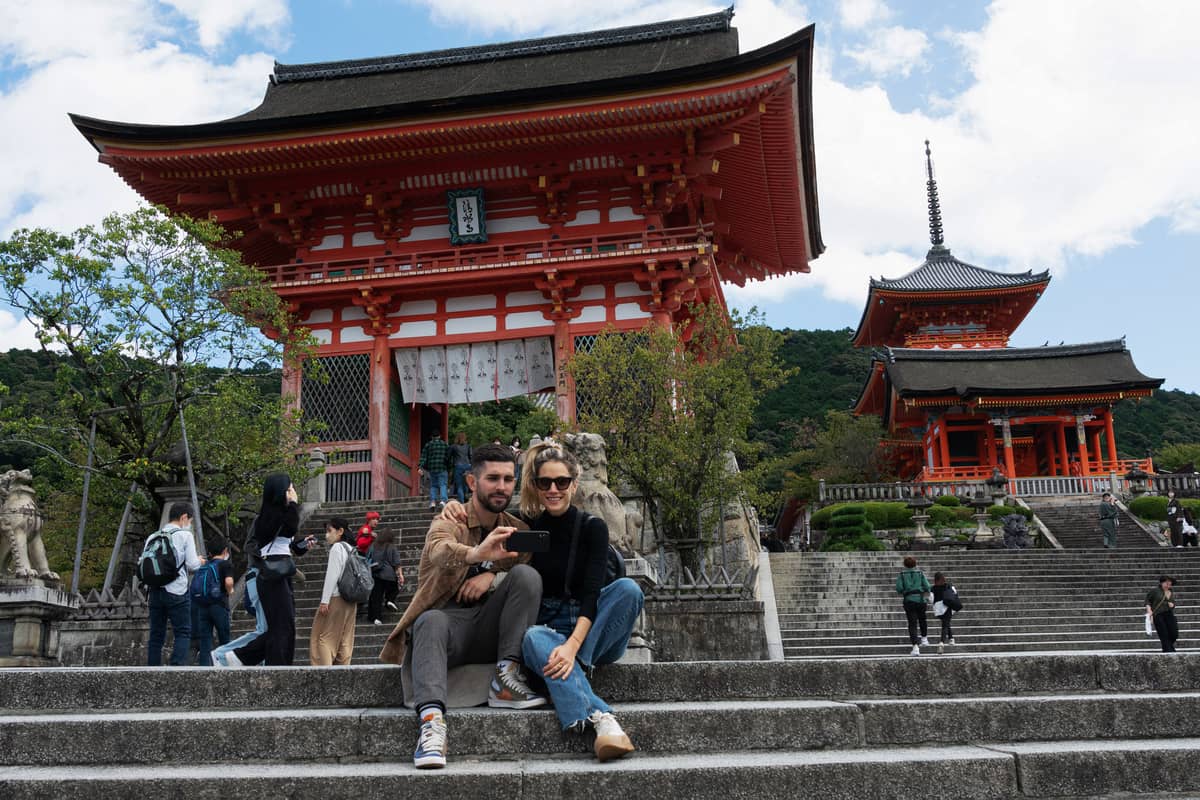 A man and woman pose for a selfie by the entrance of Kiyomizu-dera temple in Kyoto on October 11, 2022. Japan reopened its doors to tourists on October 11 after two-and-a-half years of tough Covid-19 restrictions, with officials hoping an influx of travellers enticed by a weak yen will boost the economy.