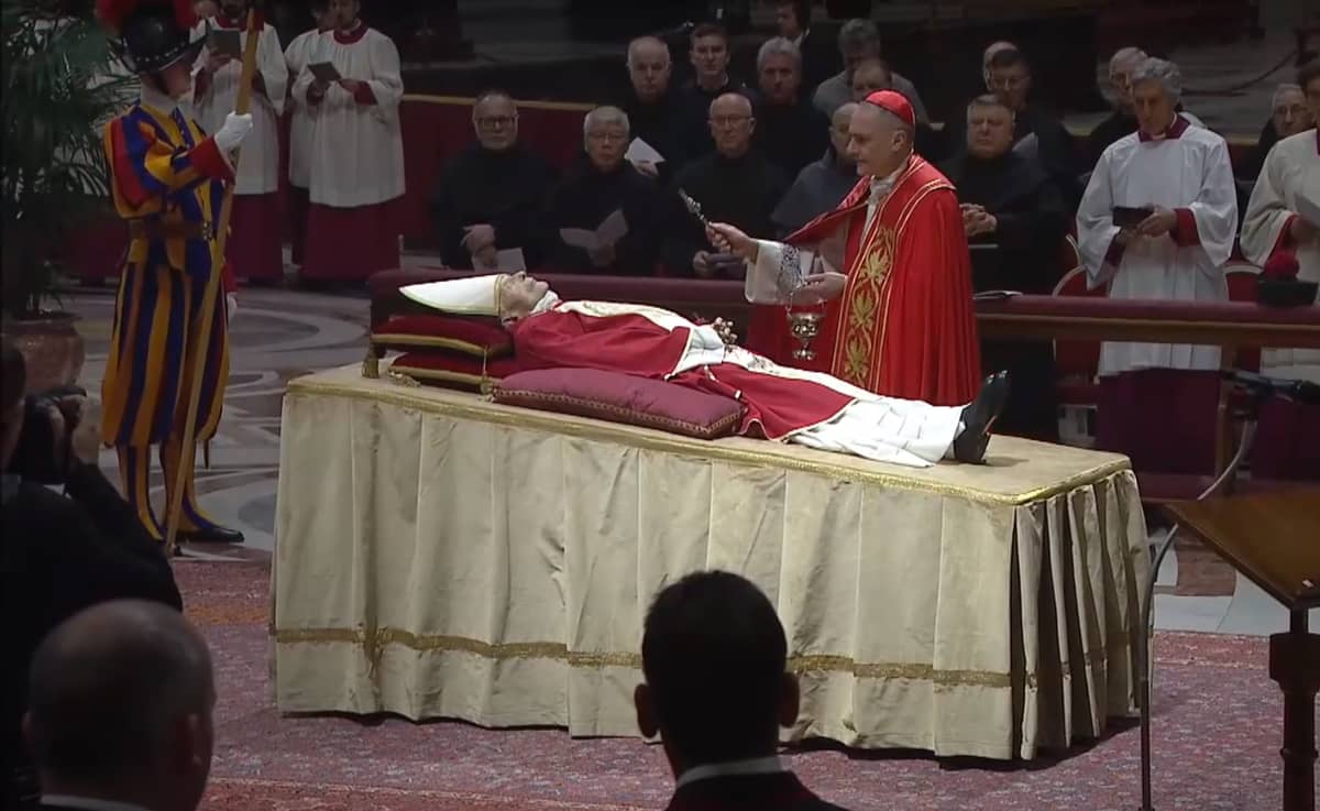 Cardinal Mauro Gambetti sprinkles water on the dead body of Benedict XVI as part of the funeral Rite of Reception