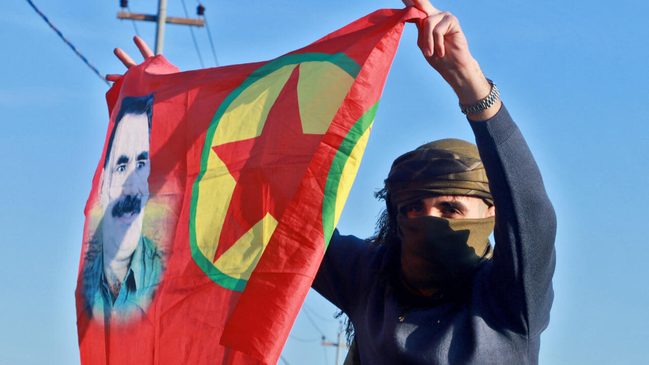 An Iraqi Kurdish woman waves a flag bearing the portrait of the founder of the PKK, Abdullah Ocalan, at a gathering in Freedom Park in Iraq's autonomous Kurdistan region on February 27, 2025.
