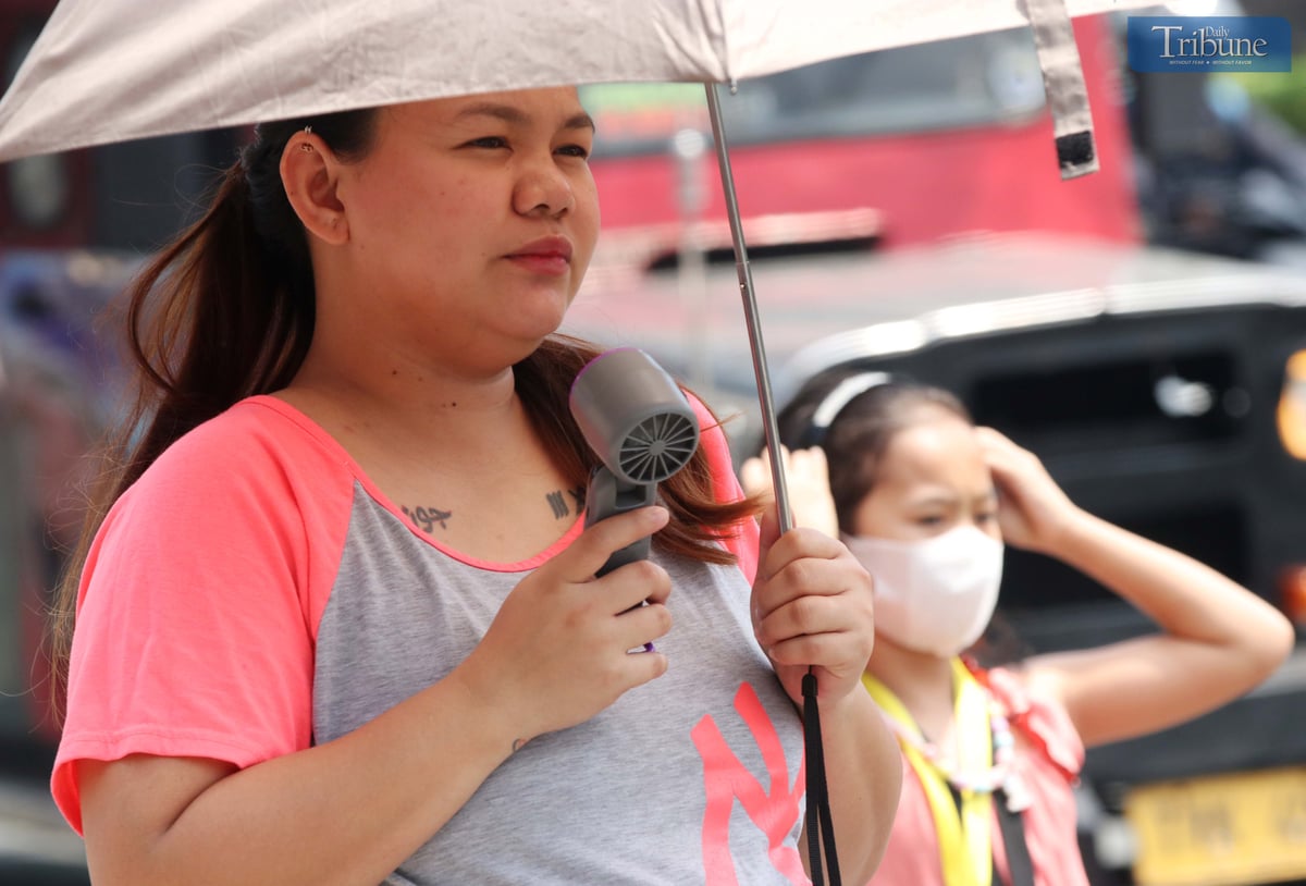 A woman uses a portable fan while walking in Quezon City on Thursday, 6 March 2025, to relieve the intense heat. The state weather bureau forecast "danger" and "extreme caution" heat index levels in several Luzon areas, including Metro Manila.