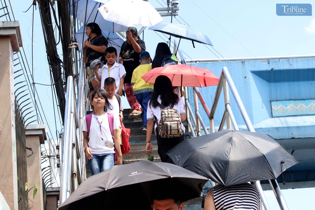 Students and their relatives shield themselves with umbrellas from the intense heat outside a school in Quezon City on Thursday, 6 March 2025. Due to the state weather bureau's forecast of "danger" and "extreme caution" heat index levels, some Luzon areas, including Metro Manila, suspended face-to-face classes.
