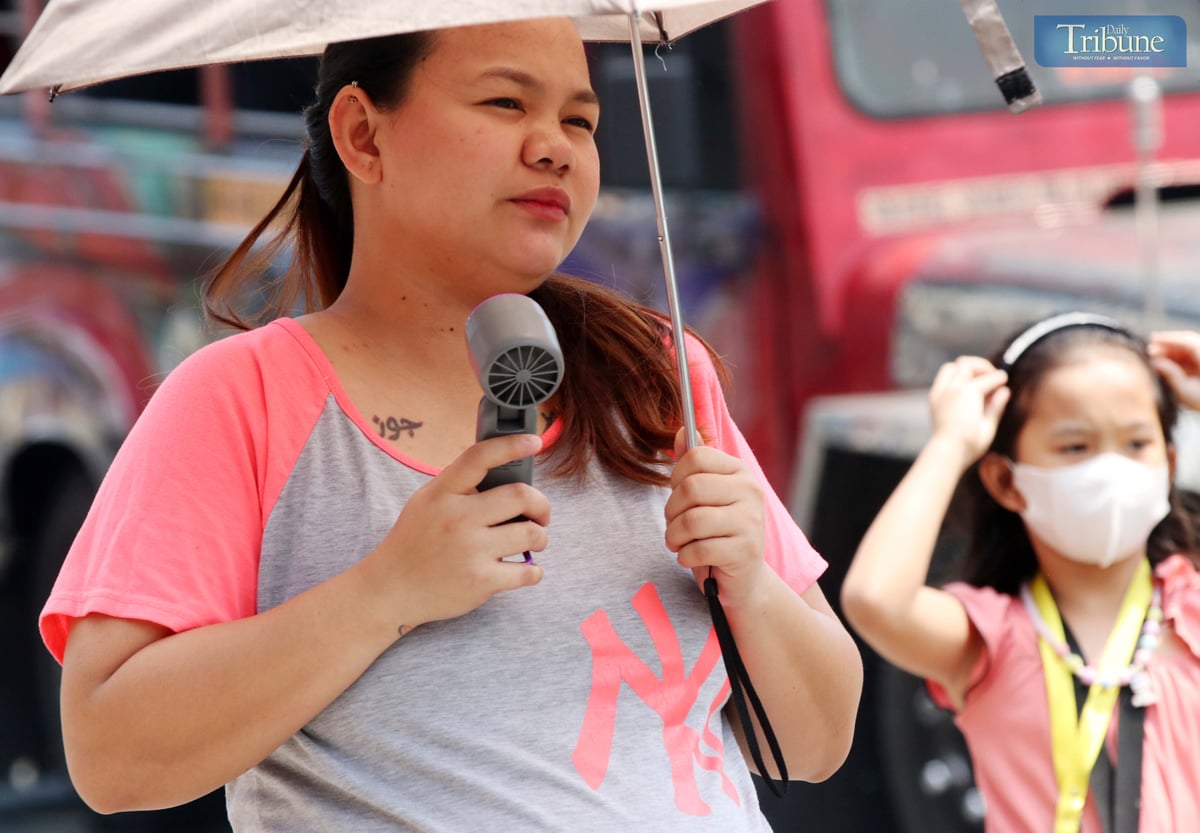 A woman uses a portable fan while walking in Quezon City on Thursday, 6 March 2025, to relieve the intense heat. The state weather bureau forecast "danger" and "extreme caution" heat index levels in several Luzon areas, including Metro Manila.