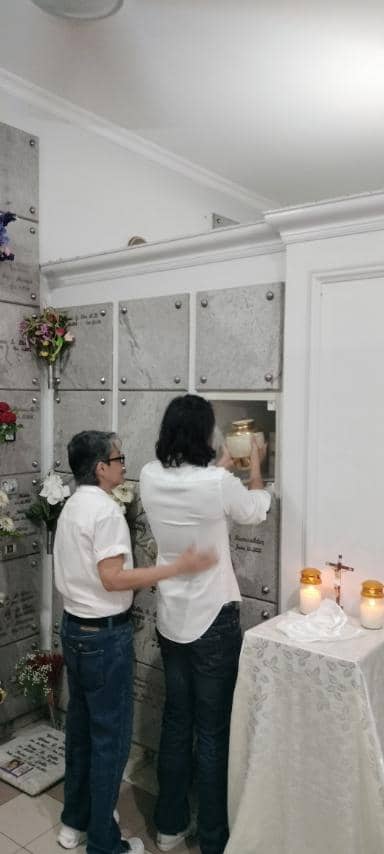 Grandson places Gloria’s urn inside ossuary.