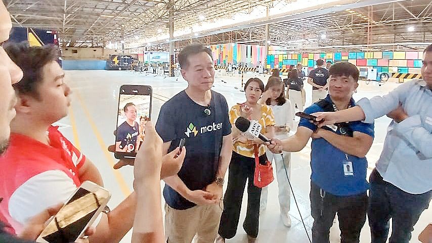 Dennis Ng, president and CEO of Mober, (center in Mober shirt) tells reporters that government and private banks must work together to unlock funding for electric vehicle operations to thrive.