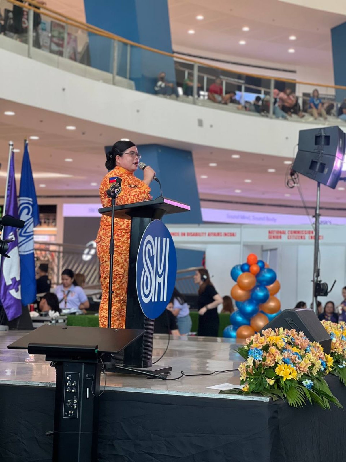 SFO3 Daisy Leal-Cabauatan delivers a lecture on "Tapang ni Juana: Women as Leaders in Disaster Resilience." Right: The Climate Change Commission booth showcases the Philippine Resilience Awards.