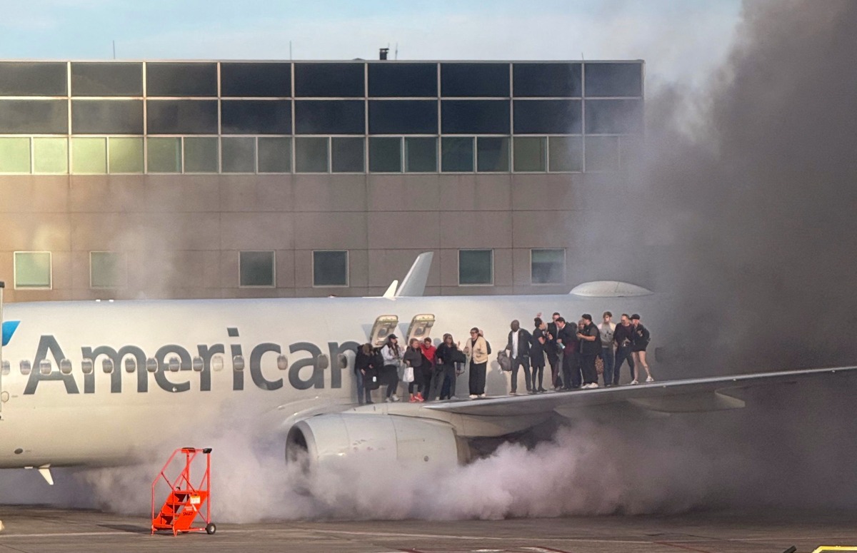 This image courtesy of Branden Williams shows passengers standing on the wing of an American Airlines plane as they are evacuated after it caught fire while at a gate at Denver International Airport in Denver, Colorado, March 13, 2025.