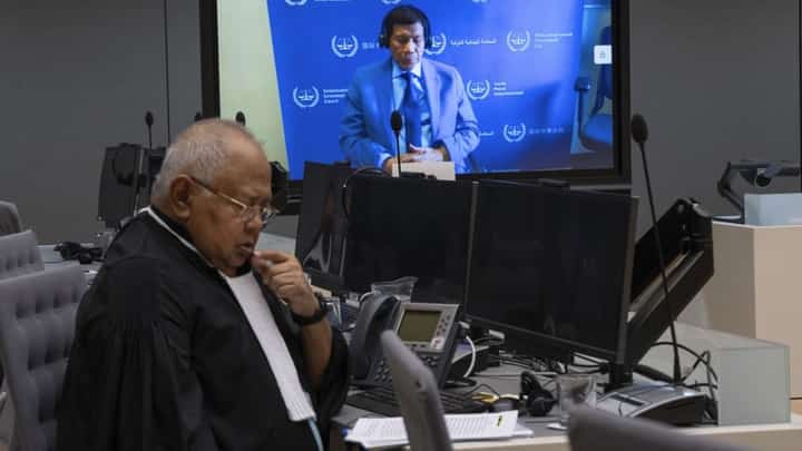 Former Philippine President Rodrigo Duterte is seen on a screen with his lawyer Salvador Medialdea (L) in the courtroom during his first appearance before the International Criminal Court (ICC) on charge of crimes against humanity over his deadly crackdown on narcotics, in The Hague on 14 March 2025.