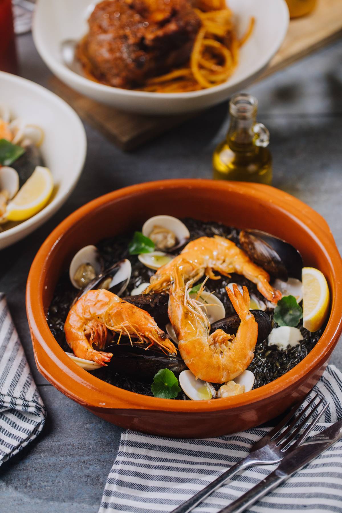 Mavros Yiouvetsi is The Greek paella negra. Grilled scallops, shrimps, clams, mussels, yogurt garlic sauce.