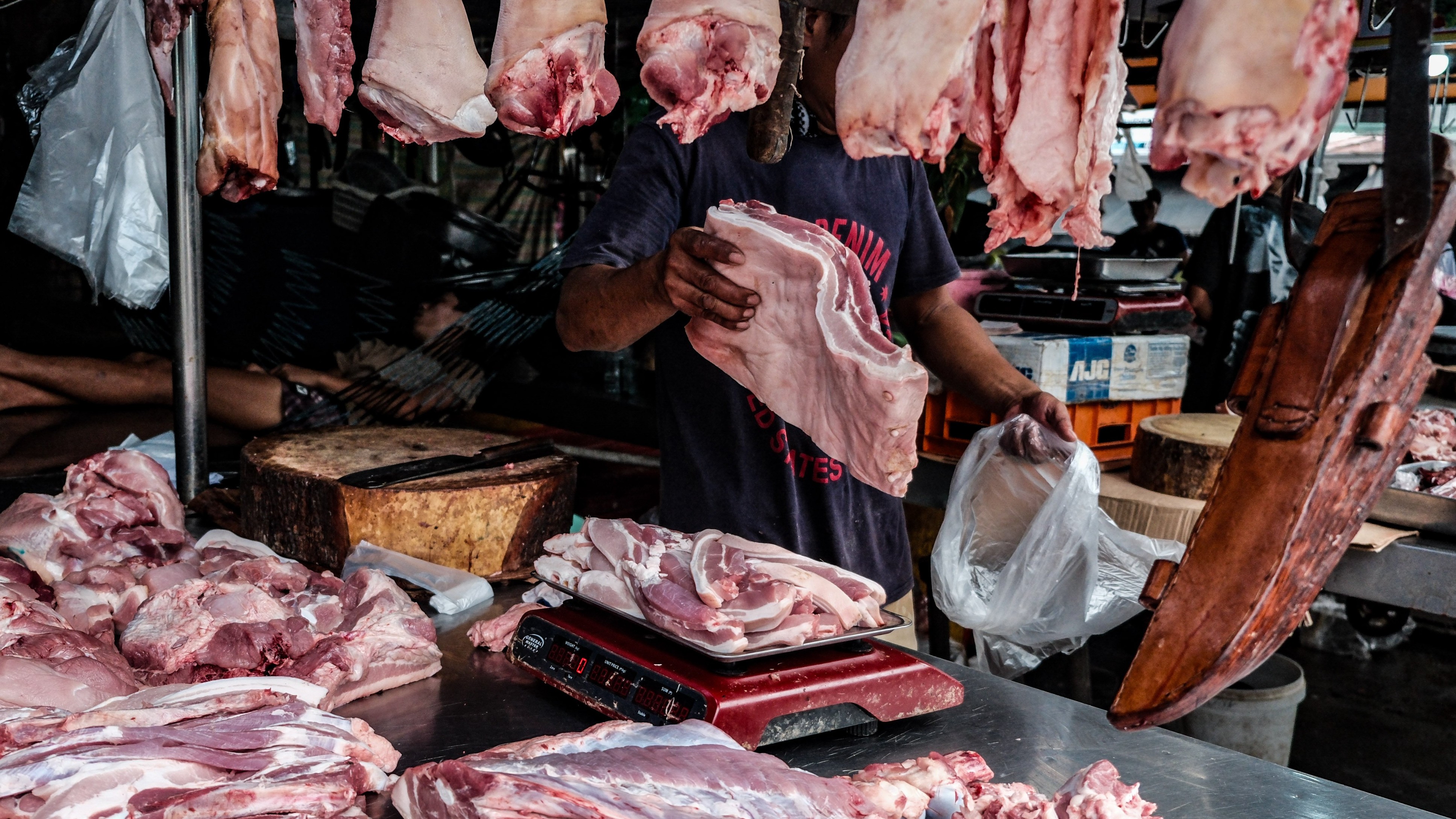 (FILE PHOTO) A meat vendor chops a pork belly upon order on 18 August, 2024. The spread of African Swine Fever (ASF) in the Philippines has led to panic among hog raisers, prompting some to sell infected pigs to traders, further worsening the situation. The Bureau of Animal Industry (BAI) has intercepted several trucks carrying pigs from ASF-hit areas, and the Department of Agriculture (DA) suspects that these traders are a major source of the virus's spread. The government is set to start vaccinating pigs soon to control the outbreak, though concerns remain about the limited availability and effectiveness of vaccines. If the situation deteriorates, the government may consider importing pigs to address potential shortages.