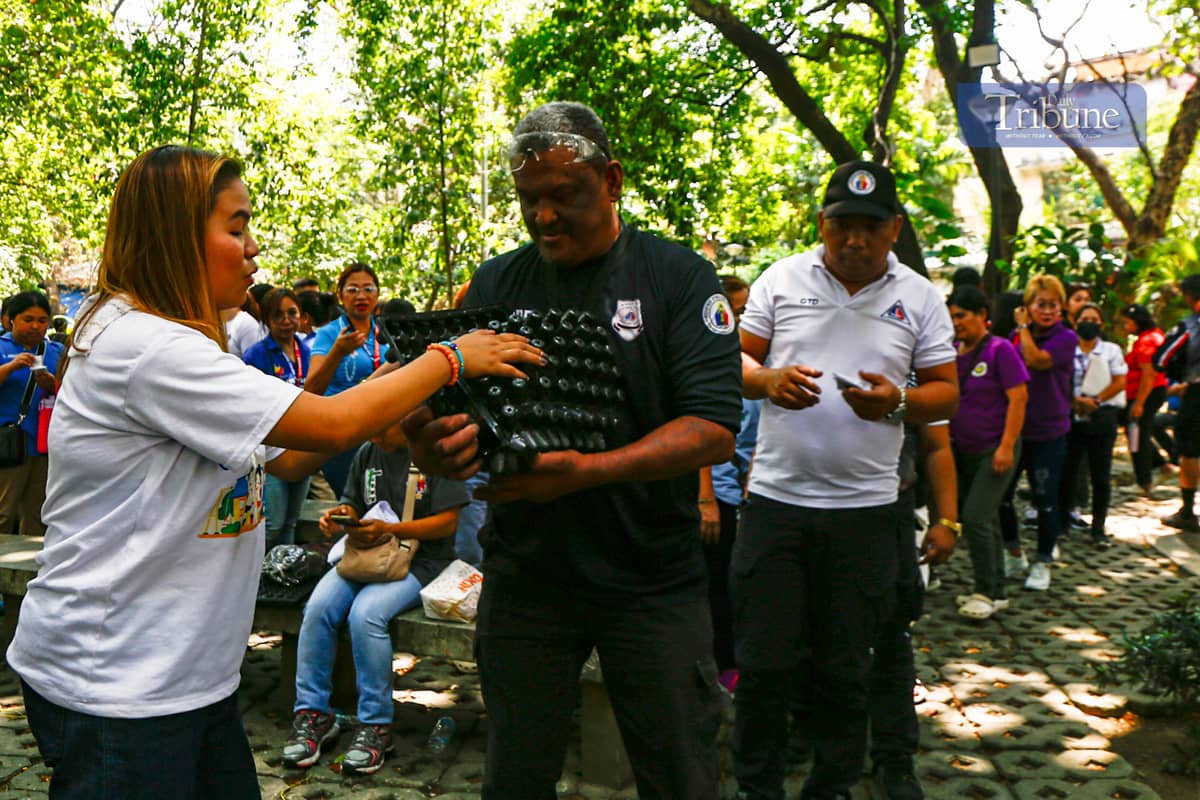 Government employees pick up free vegetable seeds and other planting materials at Quezon City's Joy of Urban Farming nursery on 25 March 2025. The city government is encouraging residents to grow organic vegetables in containers and mini-gardens.