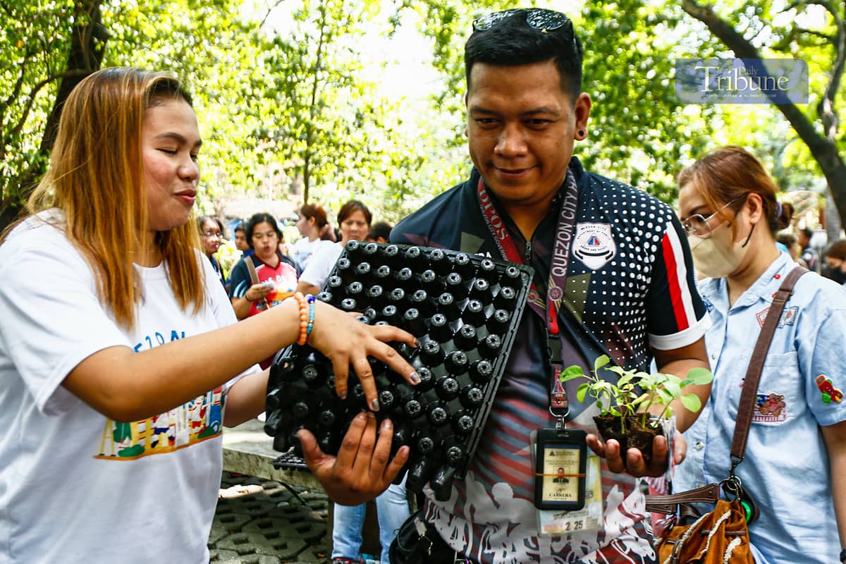Government employees pick up free vegetable seeds and other planting materials at Quezon City's Joy of Urban Farming nursery on 25 March 2025. The city government is encouraging residents to grow organic vegetables in containers and mini-gardens.
