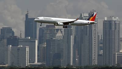Philippine Airlines Airbus A321 passenger aircraft prepares to land at the Ninoy Aquino International Airport as the skyline of the Makati business center is seen from Taguig City.
