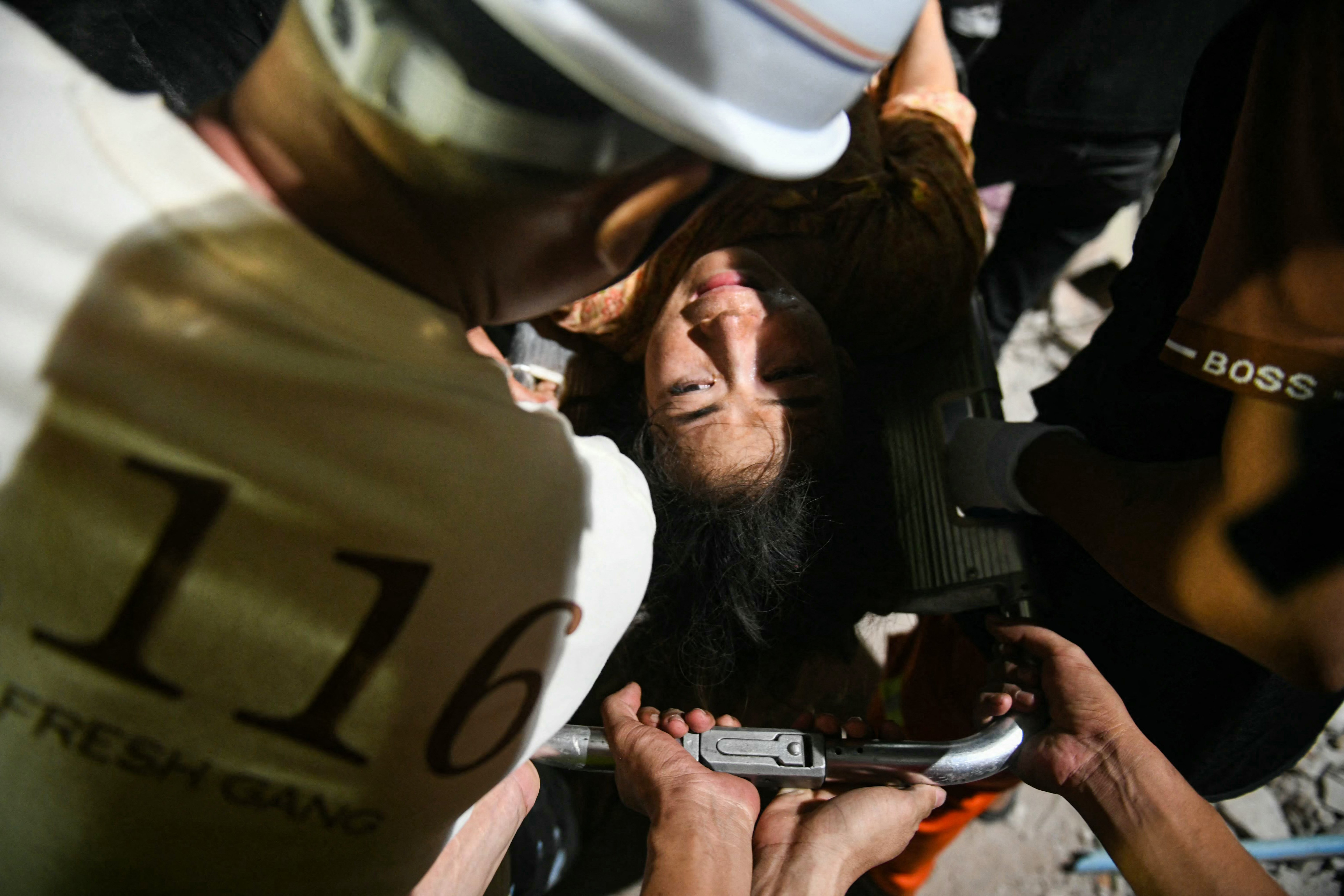 Phyu Lay Khaing is rescued from the rubble of the collapsed Sky Villa Condominium apartment building before being transported to the hospital in Mandalay on 29 March 2025, a day after an earthquake struck central Myanmar. Rescuers pulled a woman alive from the wreckage of a collapsed apartment building in Mandalay on 29 March, AFP journalists saw, 30 hours after a devastating quake hit Myanmar.