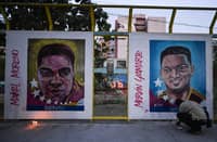 A man lights a candle in front of paintings of Venezuelan migrants deported from the US to a maximum security prison in El Salvador during a vigil in front of El Salvador embassy in Caracas on 2 April 2025.