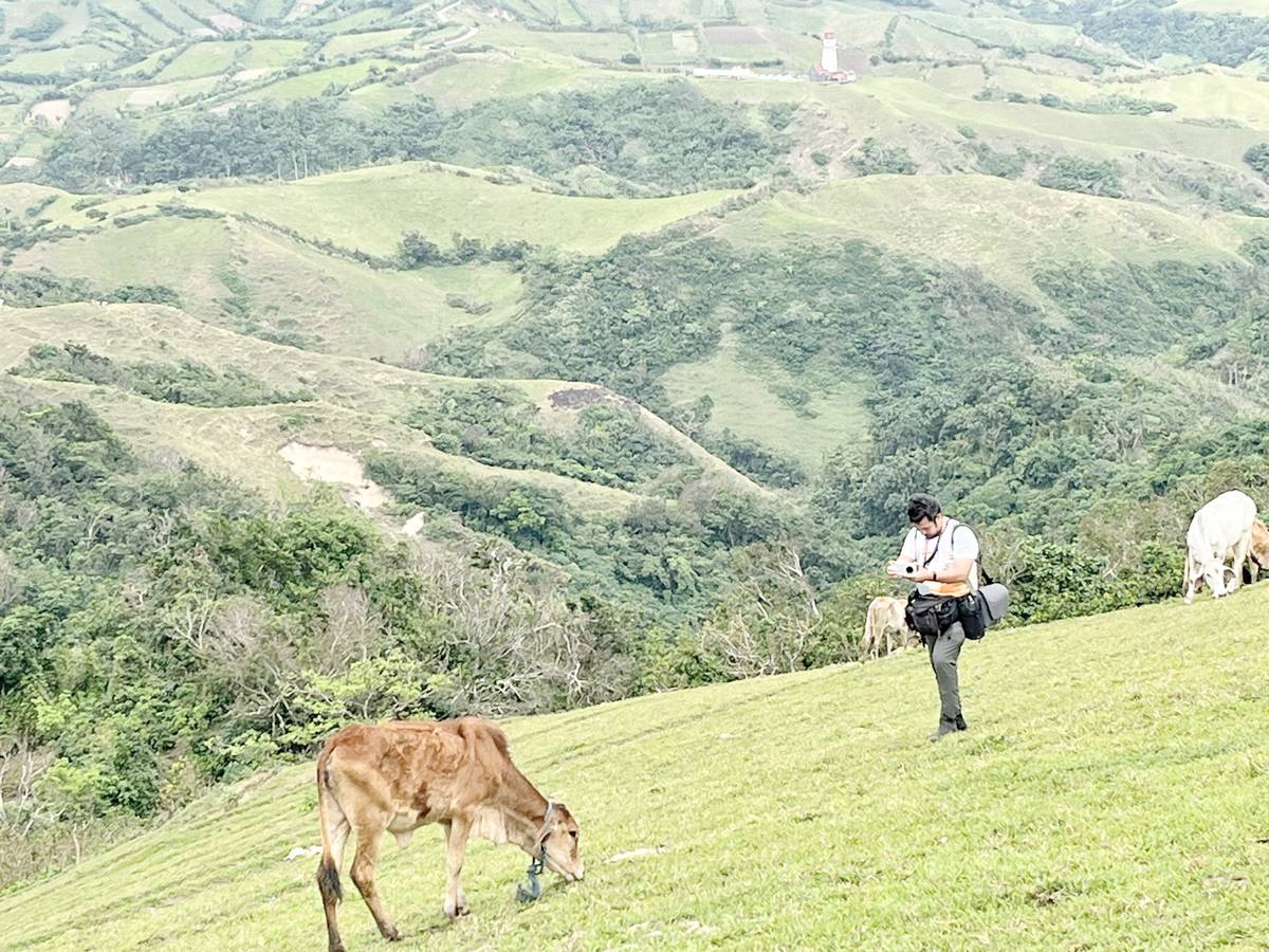 Photojournalist Mark Demayo of ABS-CBN takes shot to a cow eating grasses in Marlboro Island.