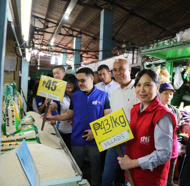 Trade Secretary Cristina Roque (in red) shows a rice price tag during an inspection in a wet market in Mabalacat, Pampanga.